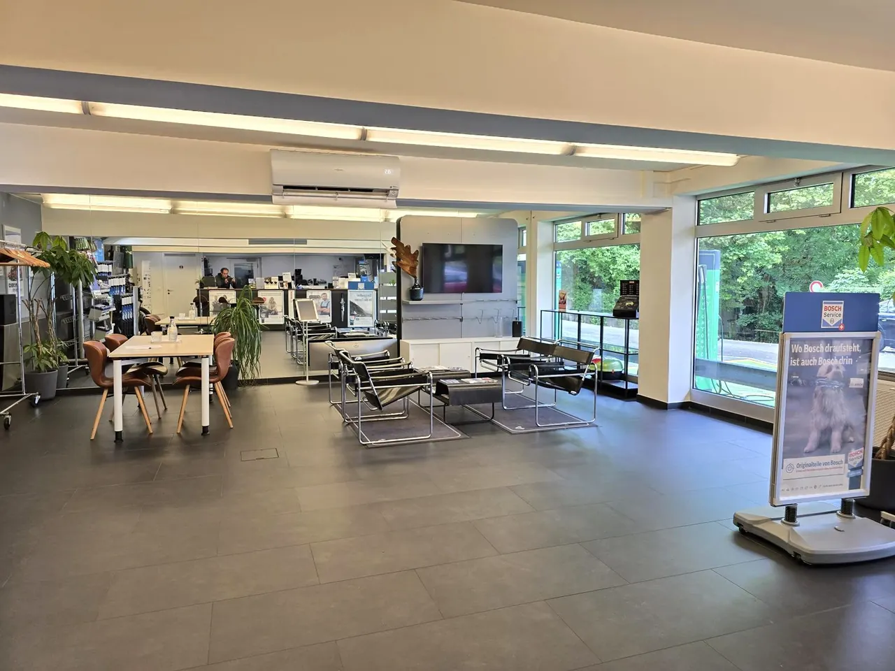 Heller Kundenbereich der Züri Garage AG mit Lounge, Empfang und Werkstatt-Sicht